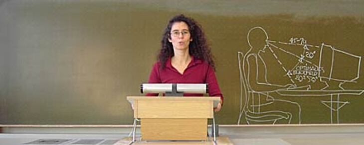 Seminarleiterin am Rednerpult vor einer Tafel